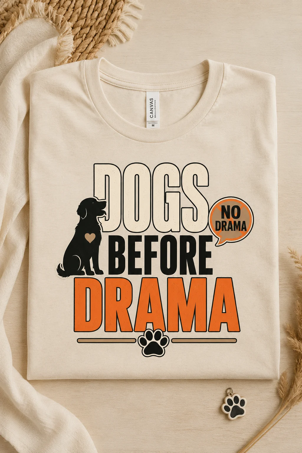 Close-up of a T-shirt displaying the bold Dogs Before Drama design with a paw detail on a warm neutral studio surface