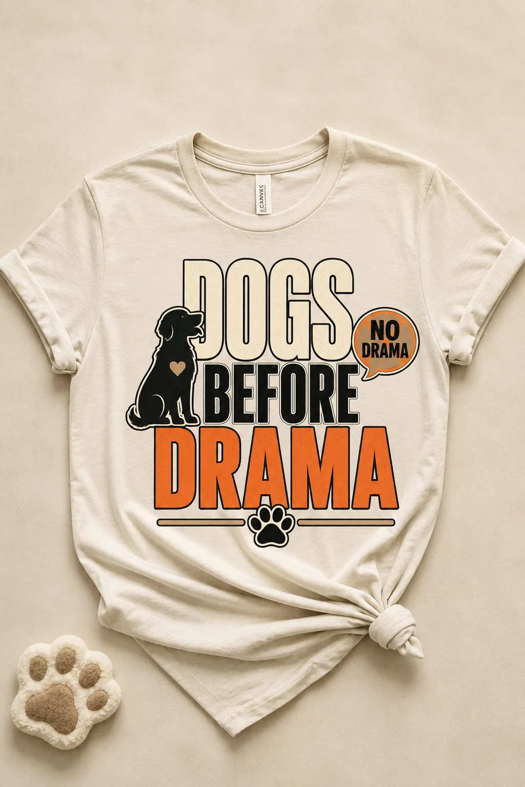Dogs Before Drama T-shirt centered against a simple neutral background with soft fabric texture and a subtle paw-print prop