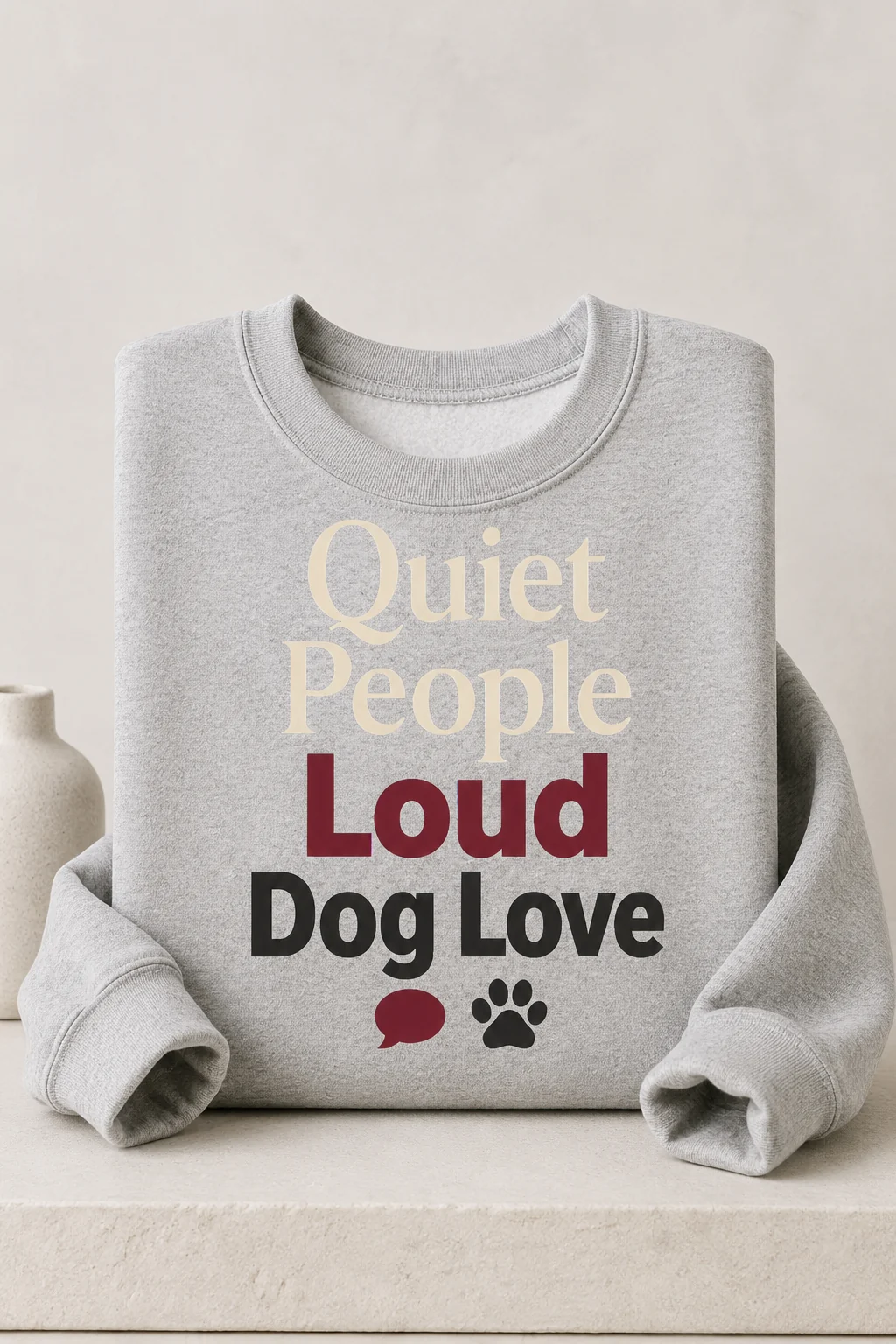 Quiet People Loud Dog Love sweatshirt displayed straight on above a minimal matte plinth with a small neutral decor object
